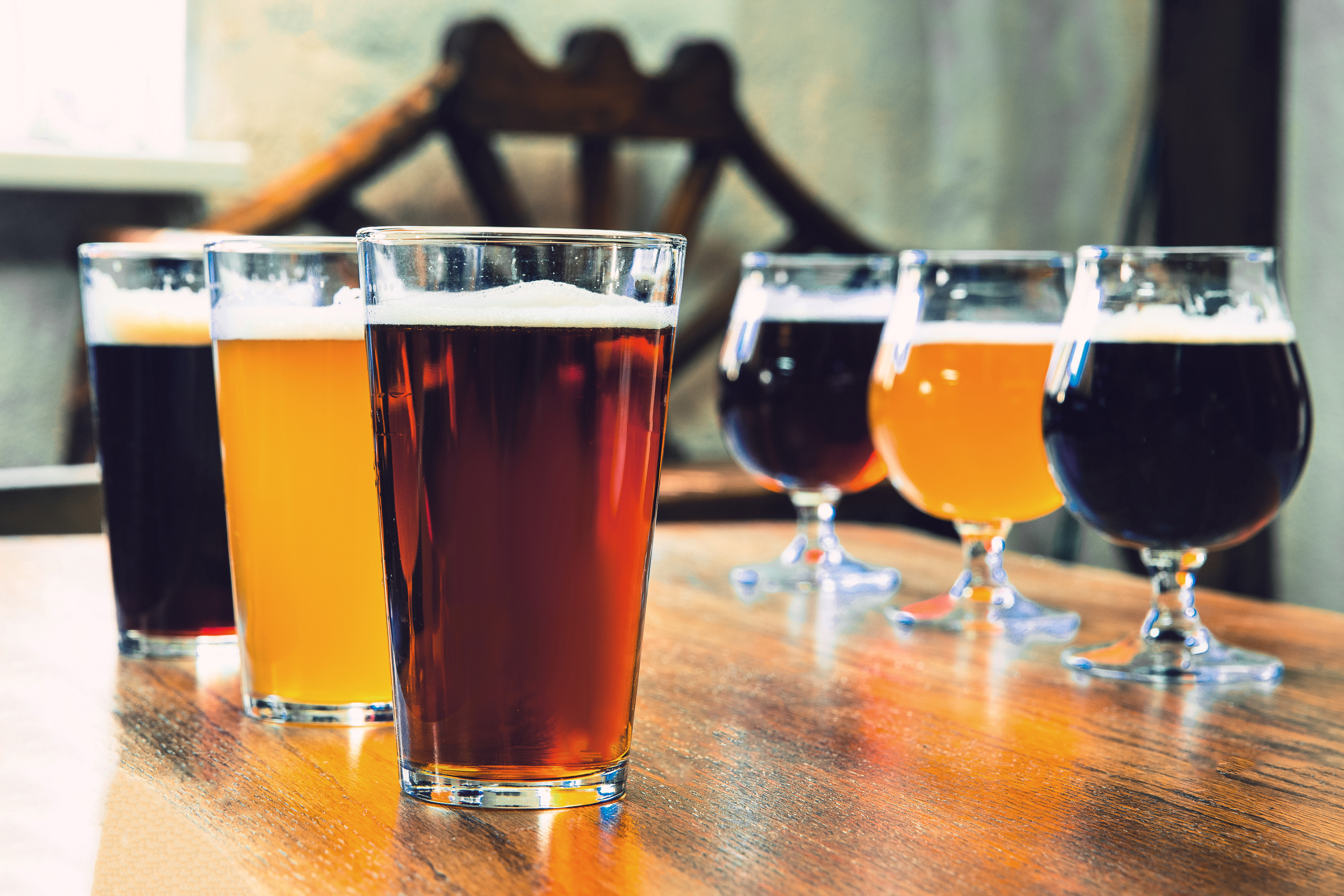 Various dark and light beers lined up on a wooden table